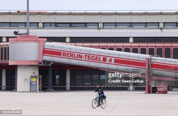 Man rides a bicycle on the deserted tarmac past Terminal A at former Tegel Airport on May 04, 2021 in Berlin, Germany. Tegel Airport, which closed to...
