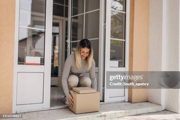 vrouw die pakket opneemt - lifting stockfoto's en -beelden