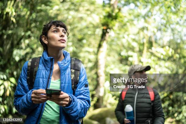 women using smartphone in a forest during hiking - explore jungle stock pictures, royalty-free photos & images