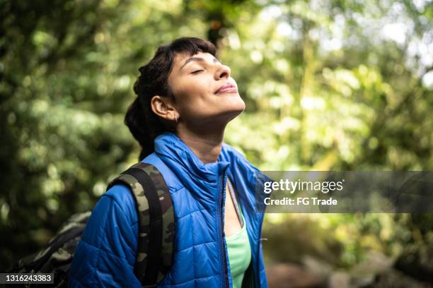 young woman breathing pure air in a forest - respirar imagens e fotografias de stock