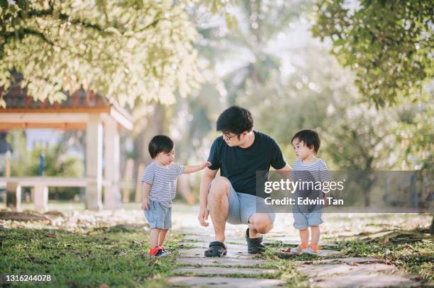 asian chinese father bonding with his twin baby boys in public park morning - asian twins stock pictures, royalty-free photos & images