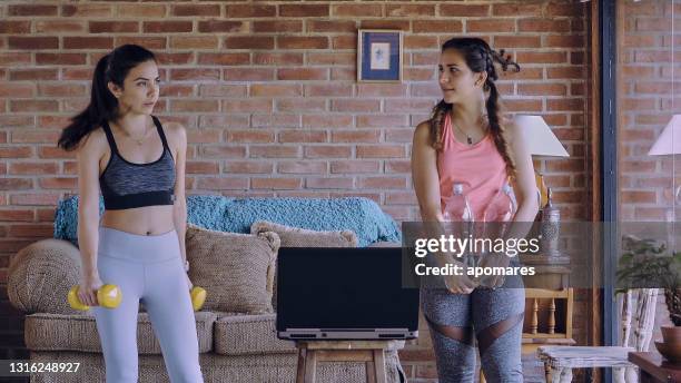 hispanic young women taking a break while exercising at home watching online tutorials - real time stock pictures, royalty-free photos & images