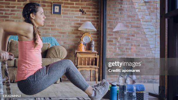 hispanic young woman exercising at home using home furniture as support - real time stock pictures, royalty-free photos & images