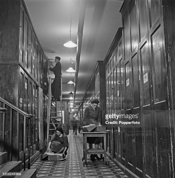 Civil servants sort and file documents in to wooden cabinets in the Archives Division at the Foreign and Commonwealth Office in Whitehall, London...