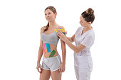 dynamic functional bandage with taping. female specialist glues kinesio tapes on the shoulder of woman