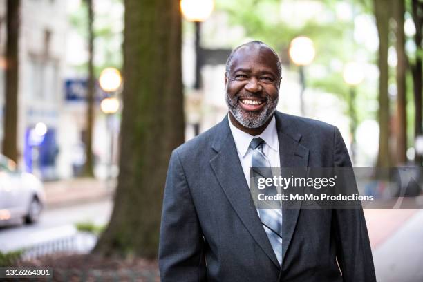 smiling senior businessman in downtown area - man in black suit stock pictures, royalty-free photos & images