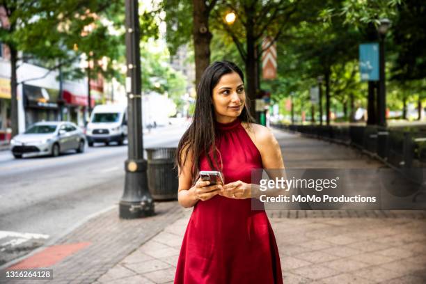 portrait of businesswoman using smartphone in downtown area - looking away stock-fotos und bilder
