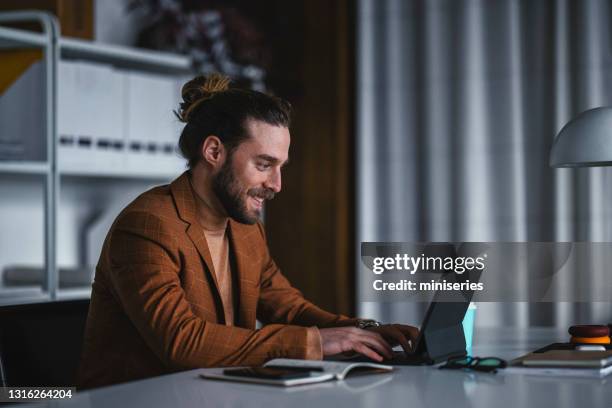 stilvoller männlicher unternehmer tippt am arbeitsplatz auf laptop - male looking content stock-fotos und bilder