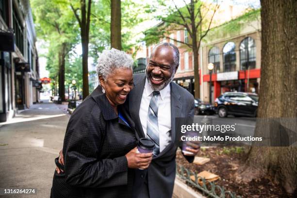 senior couple strolling through downtown area holding coffee - downtown atlanta georgia stock pictures, royalty-free photos & images