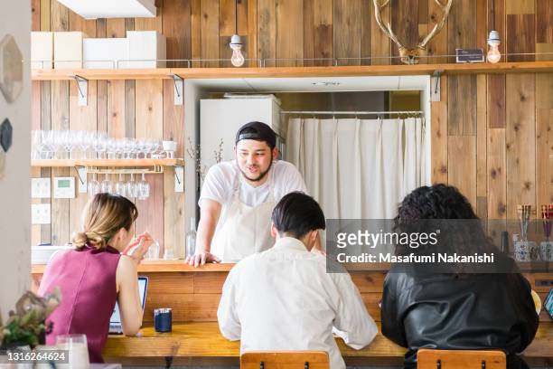 asian small business owner and his friends gathering around the bar counter in a local cafe - café bar 個照片及圖片檔