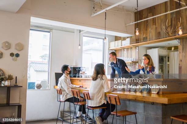 small business owners and their friends gathering around the bar counter in a local cafe - coronavirus restaurant stock pictures, royalty-free photos & images