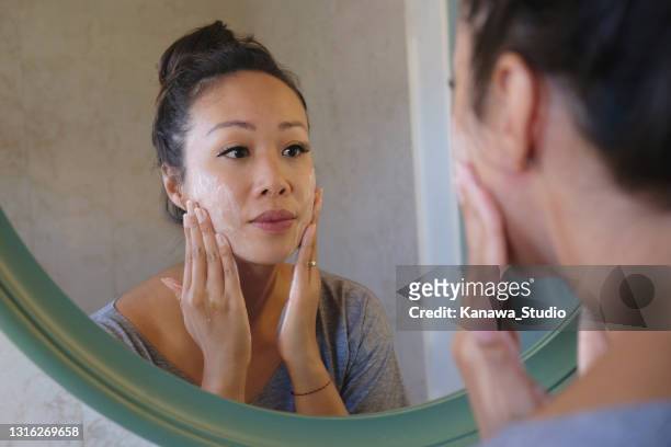 indonesische vrouw die haar gezicht met behulp van de zeep van de schoonheidsreiniger wast - facial cleanser stockfoto's en -beelden