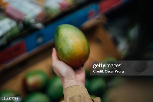 close-up shot of woman shopping fresh organic fruits in supermarket - mango stock-fotos und bilder