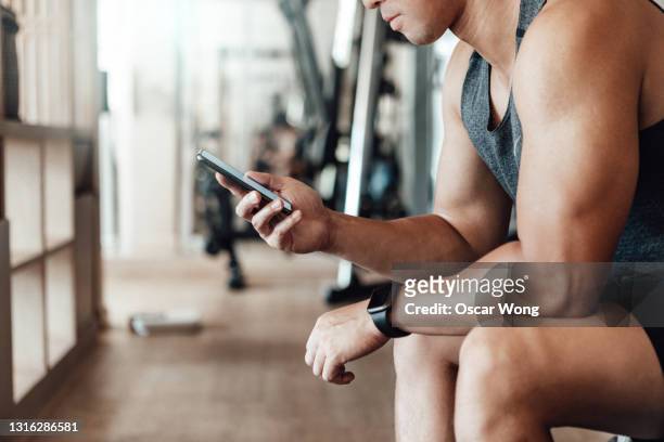 young man using smart watch and smartphone to track heart rate after exercise - asian and indian ethnicities smartwatch phone stock pictures, royalty-free photos & images
