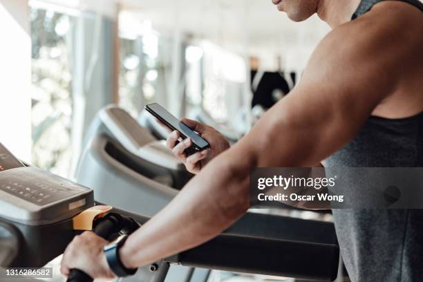 young man using smart watch and smartphone to track heart rate while doing exercise - verfolgen stock-fotos und bilder