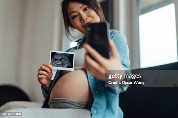 pregnant woman sharing fetal ultrasound image with family on a video call - announcement message stock pictures, royalty-free photos & images