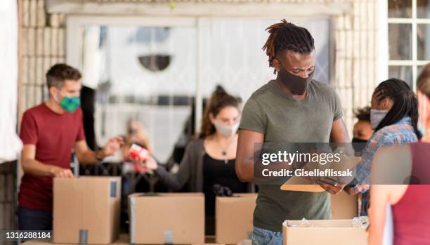 joven haciendo inventario de donaciones en un centro comunitario - ayuda humanitaria fotografías e imágenes de stock