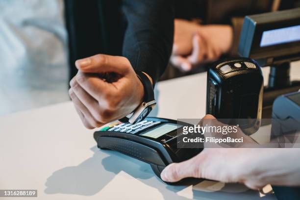 detail of a man paying contactless with his smart watch - contactless payment stock pictures, royalty-free photos & images