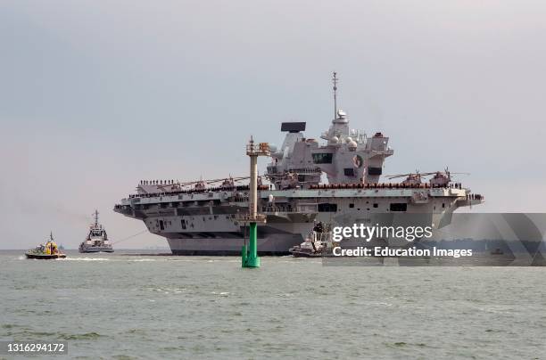 Portsmouth, England, UK, HMS Queen Elizabeth an aircraft carrier with escorting tugs departs Portsmouth Harbour towards the open sea.