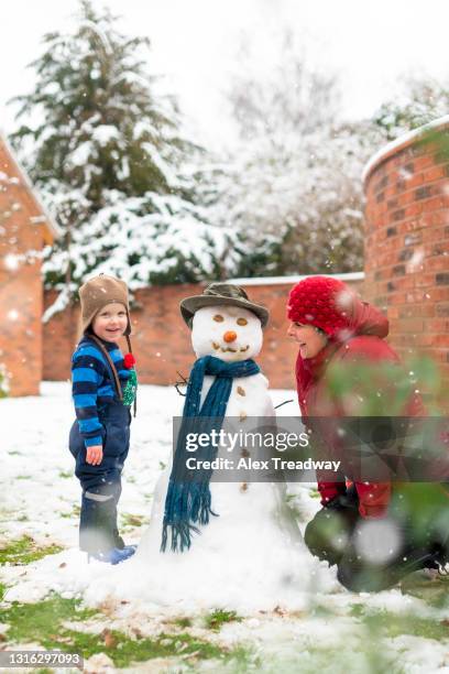 a mother daughter make a snowman together in their garden - making a snowman stock pictures, royalty-free photos & images