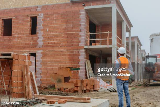 male architect examining progress work at construction site - brick house stock pictures, royalty-free photos & images