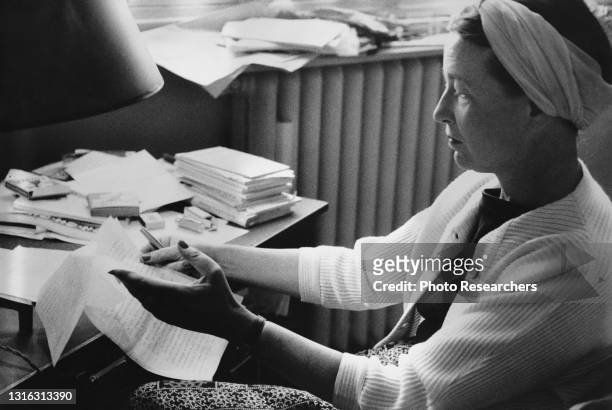 View of French writer and philosopher Simone de Beauvoir as she revises a manuscript of her memoirs, Paris, France, 1950s.