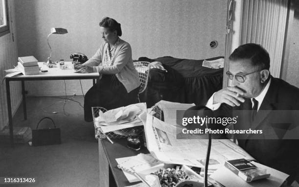 View of French authors and philosophers Simone de Beauvoir and Jean-Paul Sartre as they at their own desks in Sartre's apartment , Paris, France,...