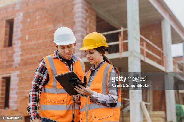 two architects using digital tablet at construction site - foundations gender equality discussion stock pictures, royalty-free photos & images