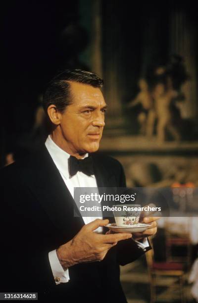 View of British-American actor Cary Grant as he holds a cup and saucer, 1950s.