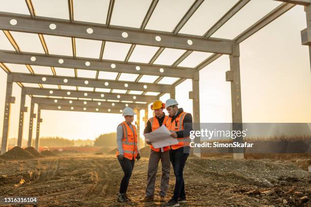 bouwondernemers die blauwdruk op bouwwerf analyseren - bouwvakker stockfoto's en -beelden