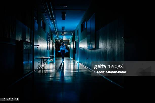 female doctor rushing down a hospital corridor - dark corridor stock pictures, royalty-free photos & images