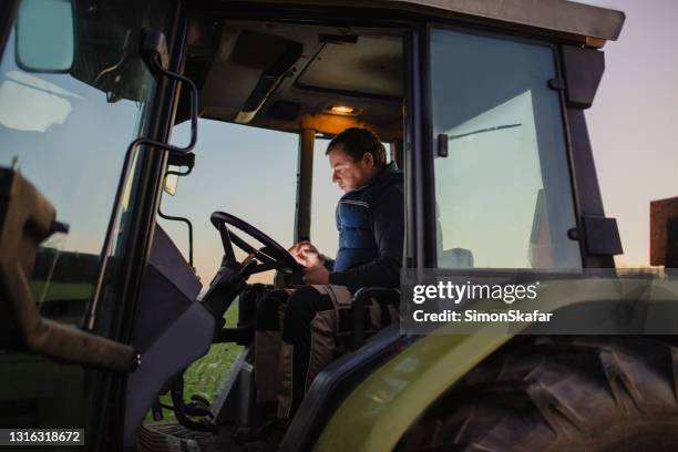 homme utilisant une tablette numérique assis dans un tracteur - agriculteur conducteur tracteur photos et images de collection