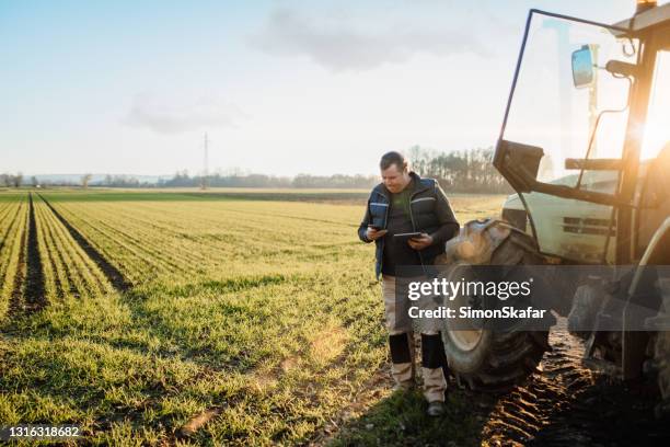 multitasking mens die mobiele telefoon en digitale tablet op gebied met behulp van - agricultural equipment stockfoto's en -beelden