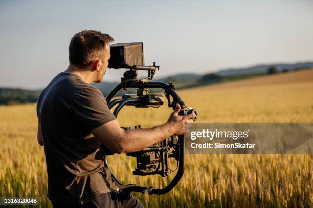 man filming on wheat field - filmar imagens e fotografias de stock