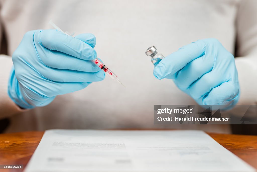 Arzt beim aufziehen einer Impfspritze gegen Corona