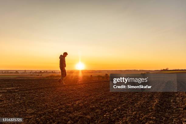 farmer walking on plowed field - farmer walking stock pictures, royalty-free photos & images