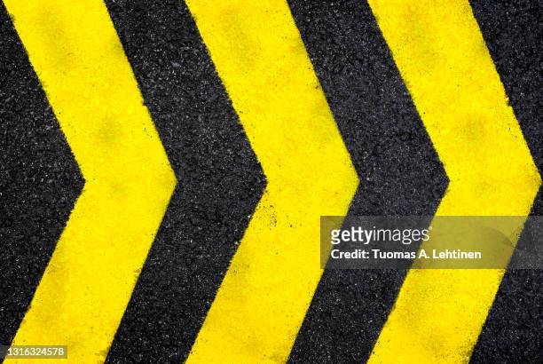 top view of dark wet asphalt road with three yellow arrow signs. - trennungslinie stock-fotos und bilder