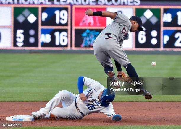Whit Merrifield of the Kansas City Royals slides under second baseman Cesar Hernandez of the Cleveland Indians for a steal in the first inning at...