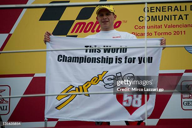 Stefan Bradl of Germany and Viessmann Kiefer Racing poses on the podium with the flag for remeber the italian rider Marco Simoncelli of Italy and San...