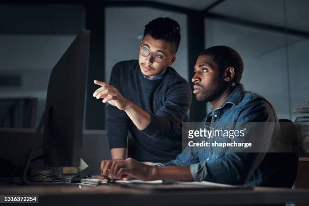 shot of two young businessmen using a computer during a late night in a modern office - using computer stock pictures, royalty-free photos & images