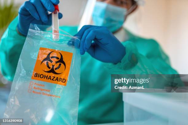 male doctor putting sample of covid-19 test in biohazard bag - biohazard symbol stock pictures, royalty-free photos & images