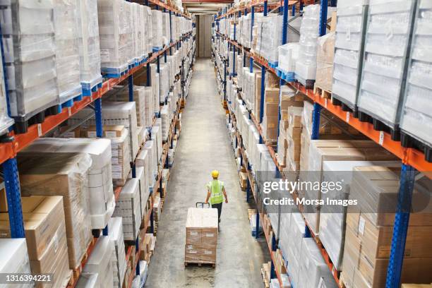 worker pulling cardboard boxes at warehouse - rack stock pictures, royalty-free photos & images