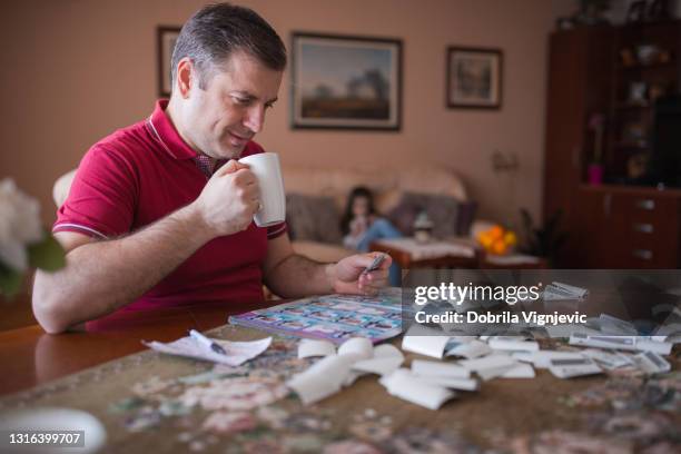 cheerful man taking a coffee break when filling in uefa 2021 sticker album at home - uefa stock pictures, royalty-free photos & images