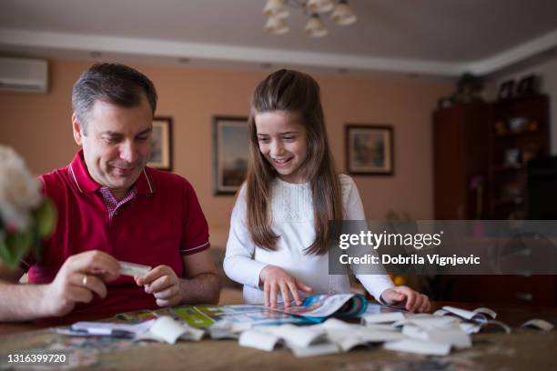 child smiling when filling in uefa sticker album with her father - uefa stock pictures, royalty-free photos & images