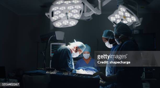 shot of a medic team performing surgery in theatre - operating room stock pictures, royalty-free photos & images