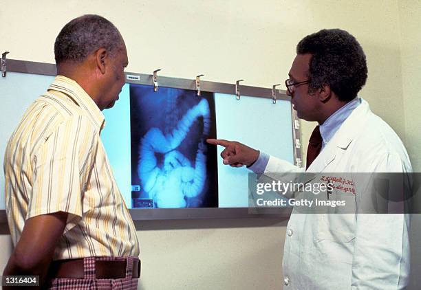 Doctor goes over a patient''s x-ray, screening for colon cancer. There is no single cause of colon cancer. Cancer of the colon and rectum accounts...