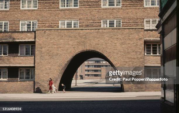 Woman and two children walk past a brick arch leading to the low rise Collyhurst Flats social housing development off the Rochdale Road in...