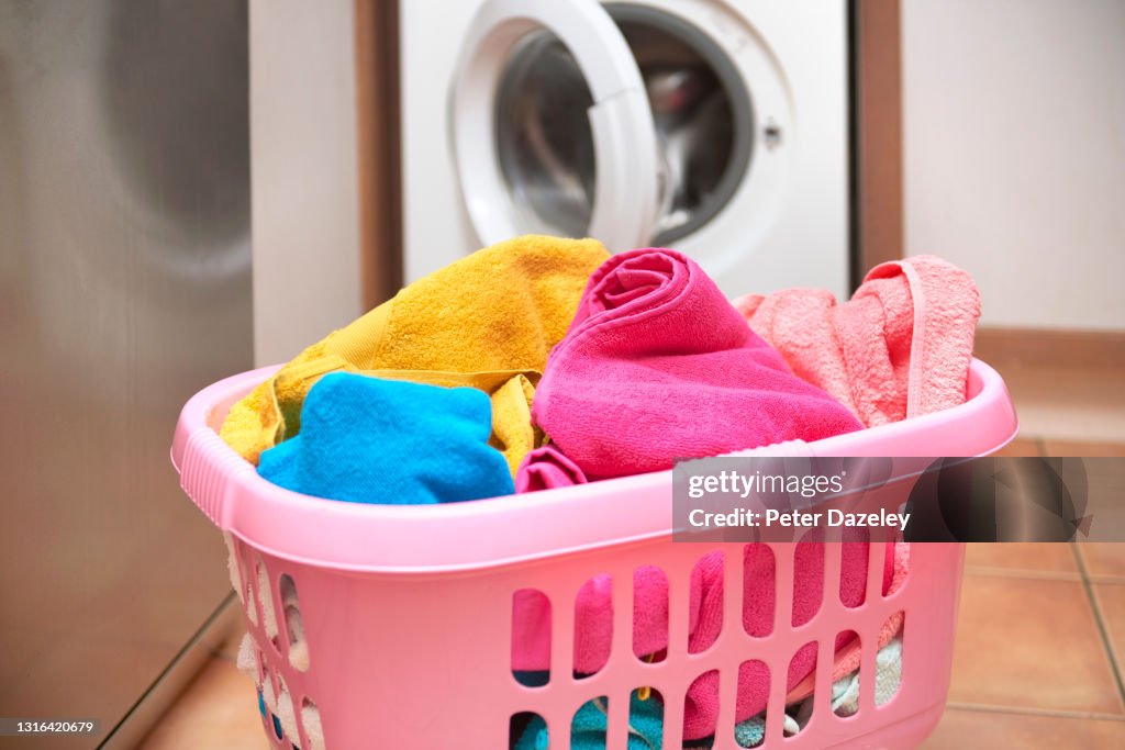 Washing in laundry basket, waiting beside washing machine