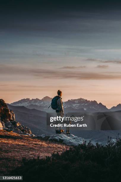 woman hiking and looking at the view on the top of a mountain with a beautiful landscape at sunrise. - picos de europe stock pictures, royalty-free photos & images