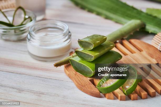 fette di aloe vera e idratante su un tavolo di legno. concetti di trattamento della bellezza - cosmética foto e immagini stock